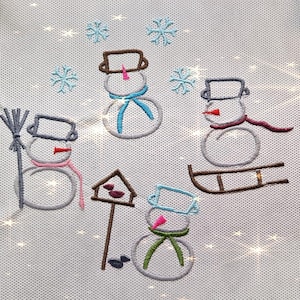 May include: Embroidered design of four snowmen on a white background. One snowman is holding a broom, another is on a sled, and the other two are standing. The snowmen are decorated with colorful scarves and hats.
