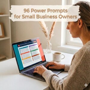 May include: A laptop screen shows a document titled "The Ultimate Small Biz Prompt Cheat Sheet" and "96 Power Prompts for Small Business Owners." A woman types on the laptop. A coffee cup and decorative plants are on the white desk.