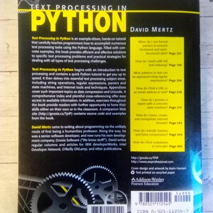 May include: A book titled "Text Processing in Python" by David Mertz. The cover is black with yellow text and features a graphic of gears. The book is published by Addison-Wesley Pearson Education.