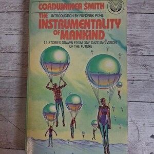 May include: A vintage paperback book titled "Instrumentality of Mankind" by Cordwainer Smith. The cover features illustrations of figures descending from green and blue hot air balloons. The book is a Del Rey SF book.