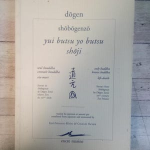 May include: A book cover with the title "Dōgen Shōbōgenzō" in a serif font. The cover includes Japanese text and English translations, with the words "yui butsu yo butsu shōji" prominently displayed. The book is white with a blue logo.