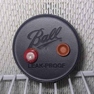 May include: Black Ball brand leak-proof jar lid with a red and white seal and a brown seal. The lid has the text "Ball" and "Leak-Proof" printed on it.