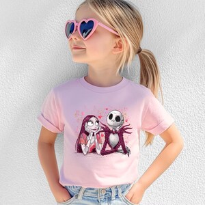 A young girl wearing a pink t-shirt with a graphic of the characters Jack Skellington and Sally from the movie "The Nightmare Before Christmas".