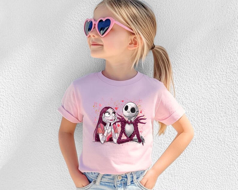 A young girl wearing a pink t-shirt with a graphic of the characters Jack Skellington and Sally from the movie "The Nightmare Before Christmas".