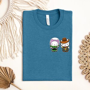 a blue t-shirt with a cartoon character design, along with some decorative elements such as a macrame wall hanging, a woven mat, and a leaf.