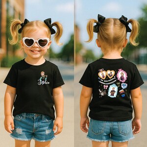 A young girl wearing a black t-shirt with a character design, sunglasses, and denim shorts is standing on a street.