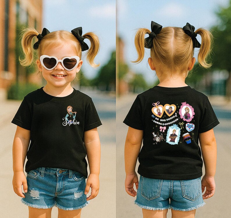 A young girl wearing a black t-shirt with a character design, sunglasses, and denim shorts is standing on a street.