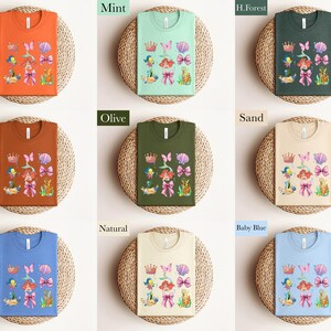 The image is a collage of nine different t-shirt designs, each with a unique color and pattern. The t-shirts are displayed on a woven basket, creating a visually appealing arrangement.