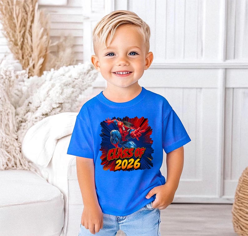 A young boy wearing a blue t-shirt with a graphic design and text, smiling at the camera.