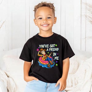 A young boy wearing a black t-shirt with a character from Toy Story printed on it, smiling at the camera.