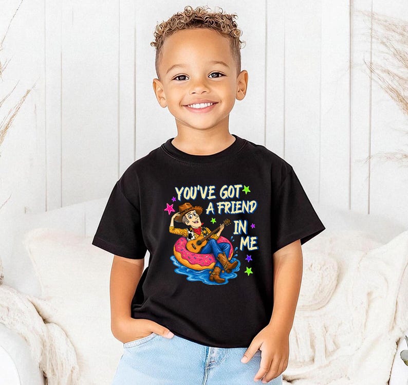 A young boy wearing a black t-shirt with a character from Toy Story printed on it, smiling at the camera.
