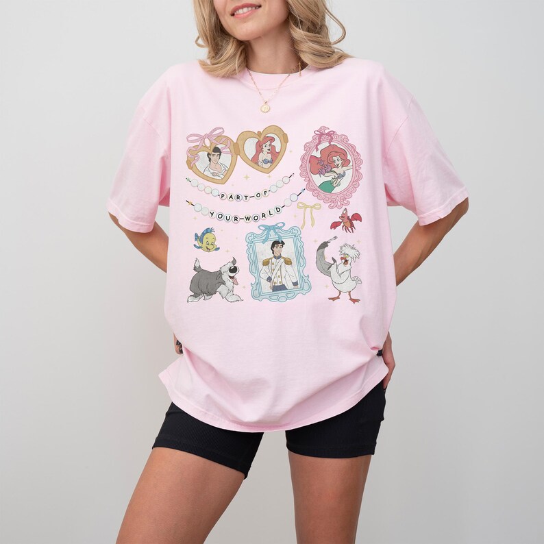 A woman wearing a pink t-shirt with a graphic design featuring characters from Disney animated films.
