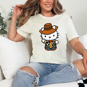 A woman sitting on a couch wearing a white t-shirt with a cartoon character and ripped jeans.