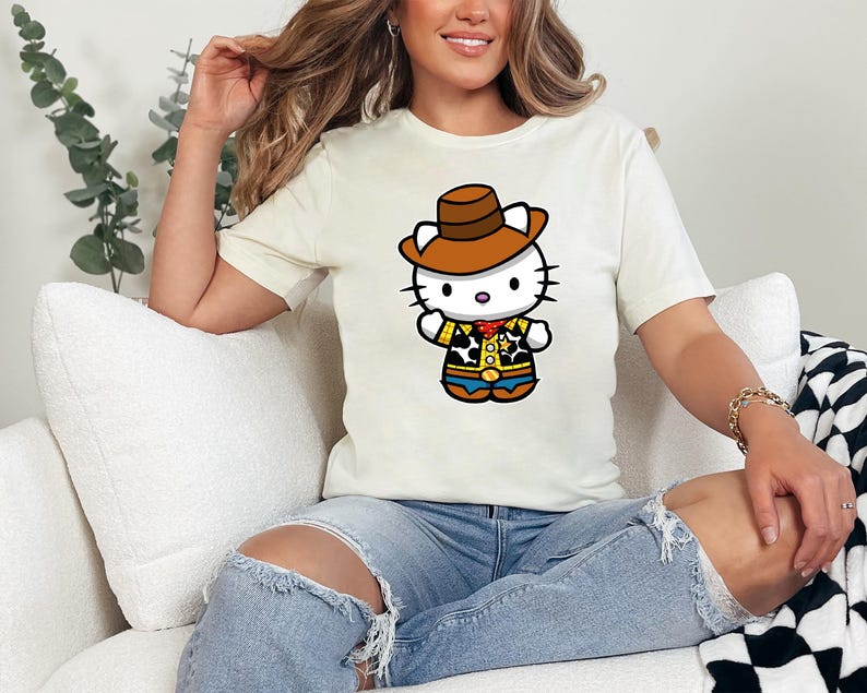 A woman sitting on a couch wearing a white t-shirt with a cartoon character and ripped jeans.
