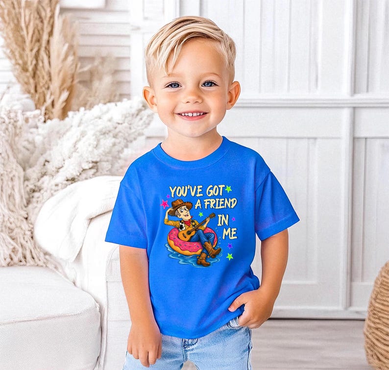 A young boy wearing a blue t-shirt with a cartoon character and text, smiling at the camera.