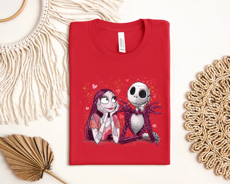 A red t-shirt with a graphic of two cartoon characters, a skeleton and a woman, sitting together.