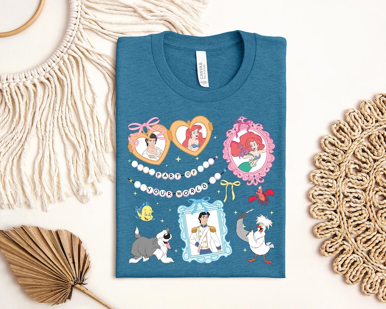 a blue t-shirt with a colorful graphic design, including illustrations of characters from Disney movies and a decorative string.