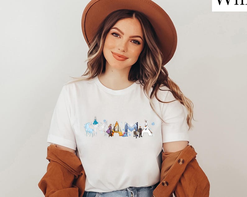 A woman wearing a white t-shirt with a graphic design and a brown hat, smiling at the camera.