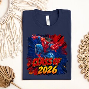 A navy blue t-shirt with a graphic design featuring a Spider-Man character and the text "CLASS OF 2026" printed on it.