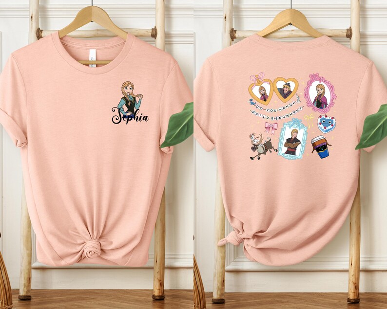 two pink t-shirts hanging on wooden hangers. The t-shirt on the left has a name tag with the name "Sophia" printed on it, while the t-shirt on the right has various cartoon-style illustrations and text on it.