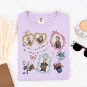 a purple t-shirt with various cartoon-style illustrations and text, including a heart-shaped character, a cup, sunglasses, and other objects.