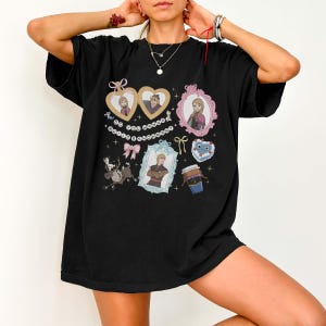 A person wearing a black t-shirt with various cartoon-style illustrations and characters on it.