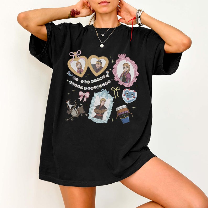 A person wearing a black t-shirt with various cartoon-style illustrations and characters on it.