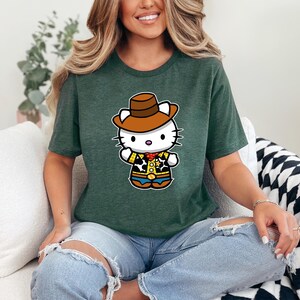 A woman wearing a green t-shirt with a cartoon character of a cat wearing a cowboy hat is sitting on a couch.