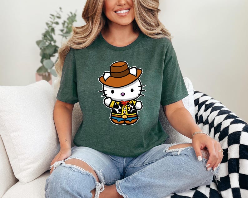 A woman wearing a green t-shirt with a cartoon character of a cat wearing a cowboy hat is sitting on a couch.