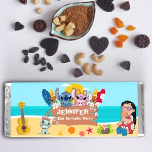 May include: A candy bar wrapper with a beach scene featuring cartoon characters. The wrapper has the name "Jennifer" and "2nd Birthday Party" printed on it. Various candies and nuts are scattered around the wrapper, including heart-shaped chocolates and dried fruit.