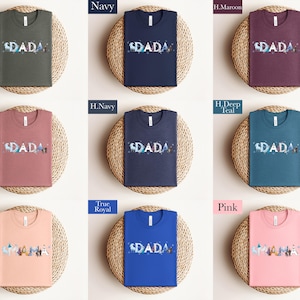 a collection of t-shirts with the word "SPADA" printed on them, arranged in a grid pattern. The t-shirts come in various colors, including navy, green, pink, blue, and purple.