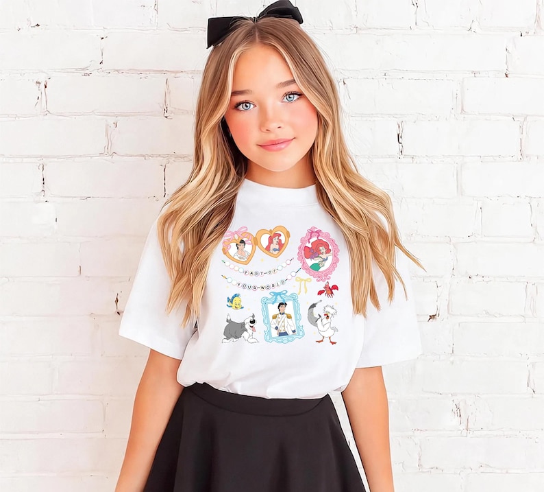 A young girl with long blonde hair wearing a white t-shirt with a graphic of Disney characters and a black skirt.