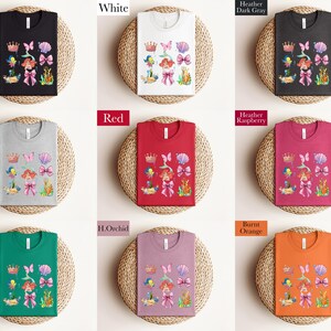 a collection of t-shirts with various colors and designs, including floral patterns and crowns, arranged in a grid-like pattern.