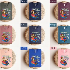 The image is a collage of nine t-shirts, each with a different color and design, arranged in a 3x3 grid. The t-shirts feature a cartoon character and the text "You've Got a Friend in Me" printed on them.