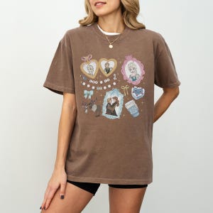 A woman wearing a brown t-shirt with various cartoon-style illustrations and characters on it.