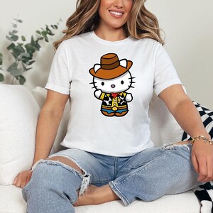 A woman wearing a white t-shirt with a cartoon character of a cat wearing a cowboy hat and a yellow shirt is sitting on a couch.