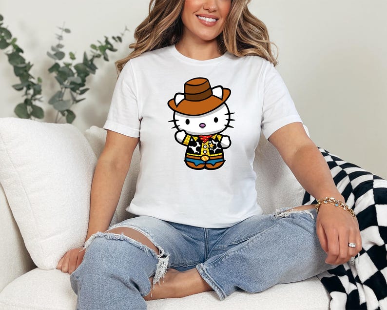 A woman wearing a white t-shirt with a cartoon character of a cat wearing a cowboy hat and a yellow shirt is sitting on a couch.