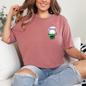 A woman wearing a pink t-shirt with a cartoon character on it is sitting on a couch.