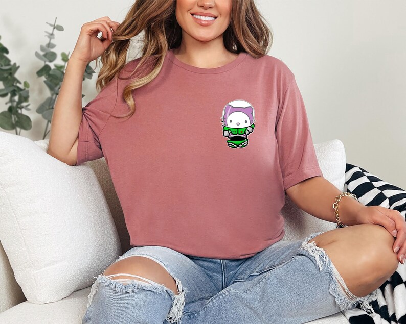 A woman wearing a pink t-shirt with a cartoon character on it is sitting on a couch.