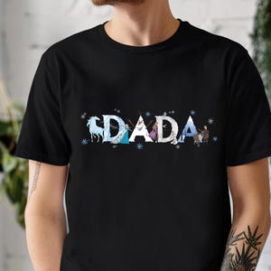 A person wearing a black t-shirt with the word "DADA" printed on it in a stylized font.