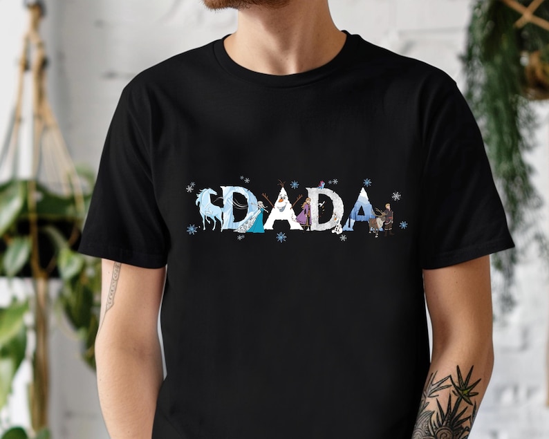A person wearing a black t-shirt with the word "DADA" printed on it in a stylized font.