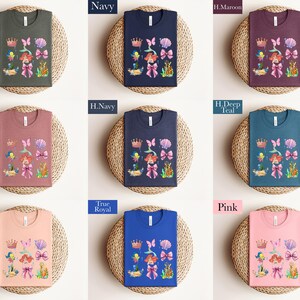 a collection of t-shirts with various colors and designs, including a mermaid theme. The t-shirts are arranged in a grid pattern, with each row containing three shirts. The shirts are placed on a woven basket or plate, which adds a rustic touch to the overall presentation.