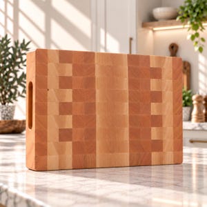 May include: A rectangular wooden cutting board featuring an end-grain construction with a checkerboard pattern of light and medium brown wood blocks. The board includes a vertical cutout handle on the left side and a thick, sturdy profile.