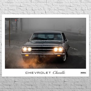Könnte beinhalten: Gerahmter Druck mit einem klassischen schwarzen Chevrolet Chevelle SS-Auto auf einer Stadtstraße. Die Scheinwerfer des Autos sind eingeschaltet, und das Bild hat eine Vintage-Ästhetik. Der Text "CHEVROLET Chevelle" steht unten.