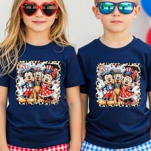 Two children wearing matching t-shirts with Mickey Mouse and Minnie Mouse graphics, along with patriotic-themed sunglasses, stand in front of a backdrop of colorful balloons.