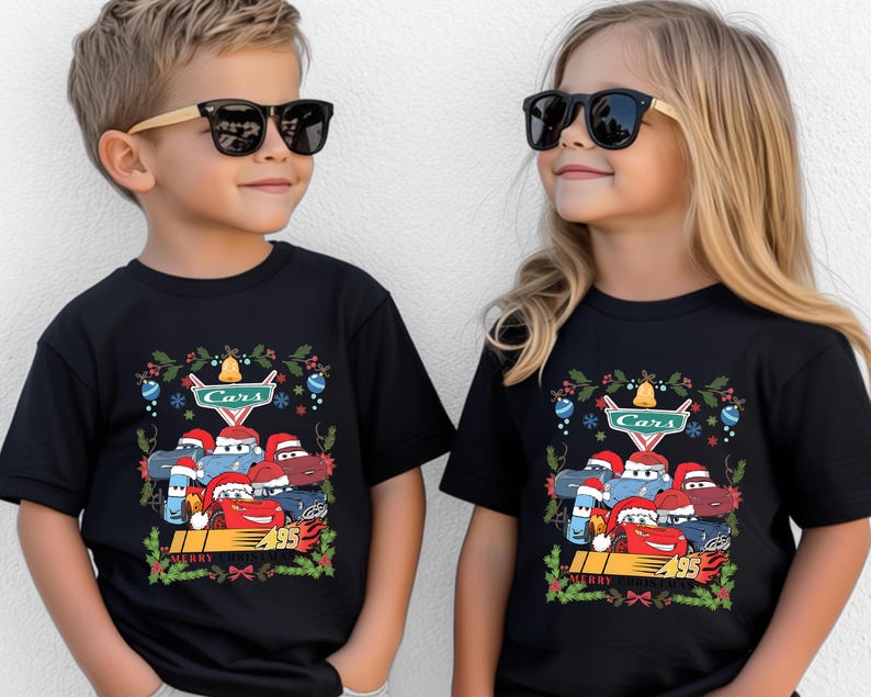Two children wearing black t-shirts with a Cars-themed design, including characters and holiday decorations.