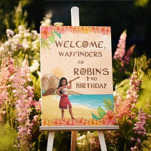 May include: A welcome sign on an easel, featuring a cartoon illustration of a character on a beach. The sign reads "Welcome, Wayfinders to Robin's 2nd Birthday" with floral and tropical design elements. The sign is surrounded by greenery and flowers.