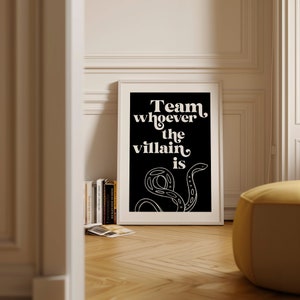 Puede incluir: Impresi&oacute;n enmarcada en blanco y negro con el texto "Team whoever the villain is" y una ilustraci&oacute;n estilizada de serpiente.