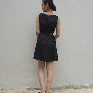 May include: A black sleeveless dress with a belt and a simple design. The dress is knee-length and has a fitted bodice.