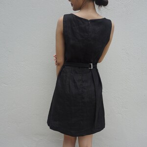 May include: A black sleeveless dress with a simple design and a belt at the waist.